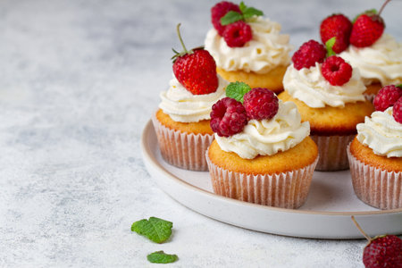Cupcakes with berries on a plate on a concrete background, copy spaceの写真素材