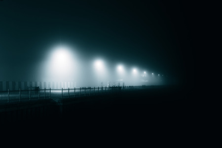 Atmospheric lampposts in the fog on the waterfrontの写真素材