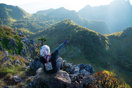 Girl sit on stone to see view of big mountainsの写真素材