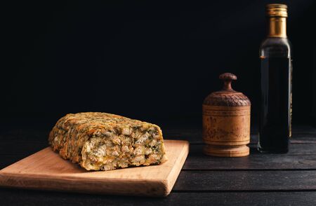 Photo of homemade Classic Bread Stuffing with chicken and balsamic on black background. Illuminated Chicken roll with decor on wooden boardの写真素材