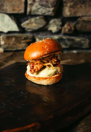 Illuminated photo of american hamburger with chuck roll meat, cheddar cheeese and other ingredietns on dark background.の写真素材