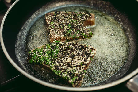 Fresh raw tuna fish steaks with pepper and other ingredients prepared for cooking. Roasted tuna fish in the frying pan on dark backgorund.の写真素材