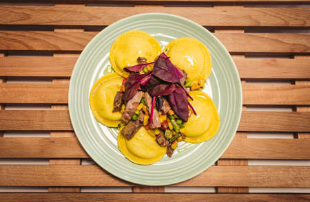 Ravioli with meat and vegetables on rustical plate and wooden table. Italian pasta - food concept.の写真素材