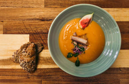 The cod fish fillet with orange soup from sweet potatoes and other tasty ingredients. Top view of food with fresh baguette on wooden background - photo from above.の写真素材