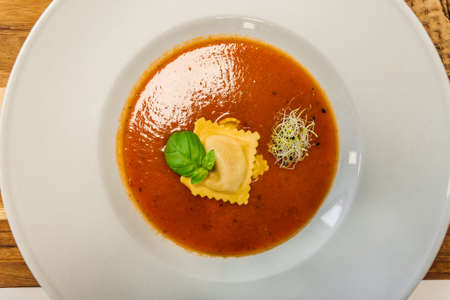 Tomato soup or gazpacho soup with Ravioli and basil on a wooden rustic table - top view.の写真素材
