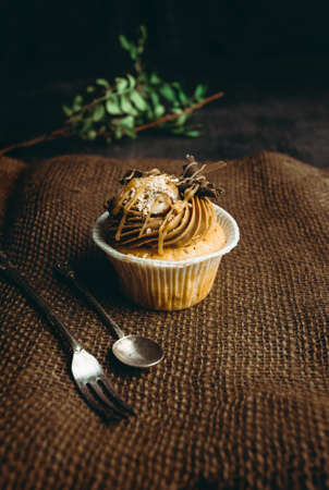 Beautiful and delicious cupcake on dark and rustical background. Cupcake with cream cheese and strawberries. Cupcake with chocolate and caramel.の写真素材