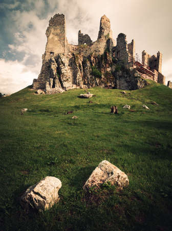 Scenic view of Hrusov Castle in Europe (Slovakia) after the storm on sunny day. Rocks and wood under the hill with castle (ruins) on background. Romantic place - castle on the hill with misty sky.の写真素材