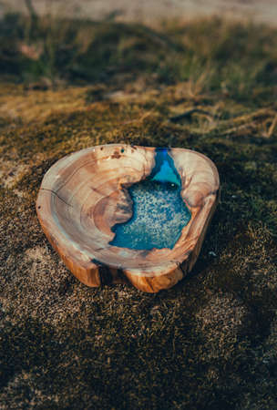 Handmade wooden bowl with blue epoxy in the nature (forest).の写真素材