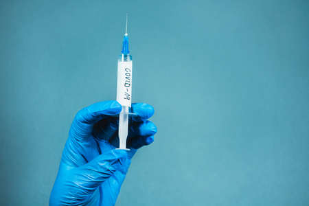 Illuminated photo of Doctor in surgical gloves is holding a vaccination syringeの写真素材