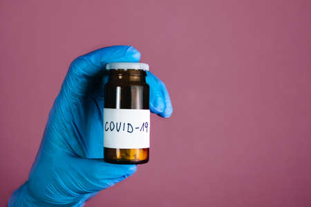 Illuminated photo of Doctor in surgical gloves is holding bottle of drugs (medicament, pills and tablets) for treatmentの写真素材