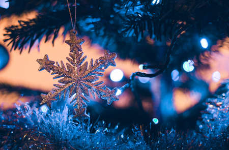 Luxury Silver christmas snowflake on christmas tree branch with blue lights on dark background. Christmas decoration - illuminated with soft light.の写真素材