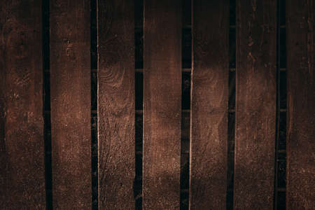 Photo of vintage wooden board with rough texture with empty space for your text or image. Illuminated dark brown wooden wall (background) - natural and soft light in the middle.  The old surface.の写真素材