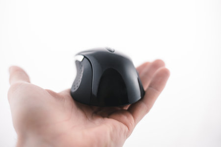 Man is holding a wireless pc mouse in opened fistful (isolated on white background). Photo of black...