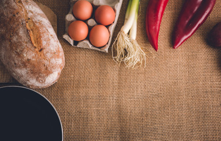Photo of various fresh vegetables, bread, eggs and pan on the table covered with jute. Photo of food...