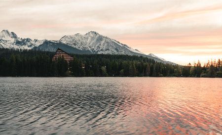 Beautiful lake in autumn scenery with amazing snowy mountains on background. Strbske pleso in High Tatras in fall with water reflection at sunrise.の写真素材