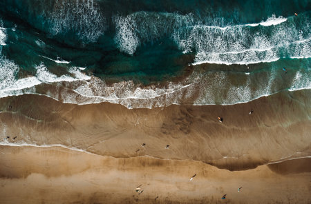Top view by drone of yellow sand beach with ocean and waves. Beach with a lot of surfers and people...