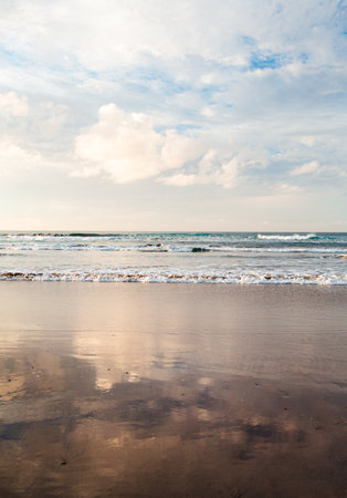 Vertical photo of empty and calm beach with ocean on background at sunset.の写真素材