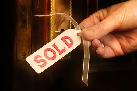 Key to new home, concept of buying or selling houses. This picture has a dreamy  Ethereal quality to the edges ,and a gold tint. The key and hand have not been filtered. Edges fade to black.の写真素材