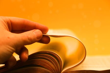Hand turning pages of the bible - gold bible.