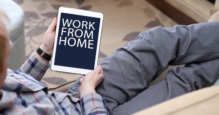 Work from home text on tablet as man relaxes in seat.の写真素材