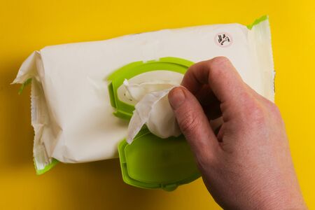 hand taking baby wipes over yellow background - open pack of baby wipes.の写真素材