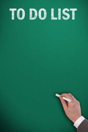 to do list on green chalkboard and an hand with chalkの写真素材