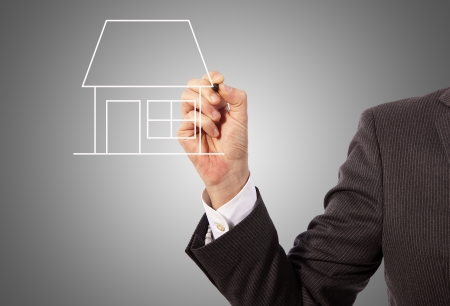 Male hand drawing a house on glass board, grey backgroundの写真素材