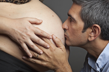 Loving father kissing the belly of his pregnant wifeの写真素材