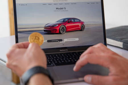 A man considers buying a tesla by paying with Bitcoins. Tesla allows you to buy products with cryptocurrencies.のeditorial素材