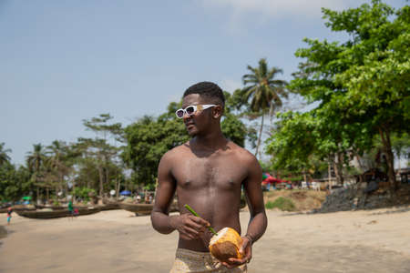 Young African boy uses his laptop while he is in an open air park. Young people and technology in africaの写真素材