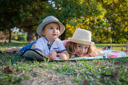 Brother and sister are lying on their stomachs during a picnic and having fun, young siblings togetherness conceptの写真素材