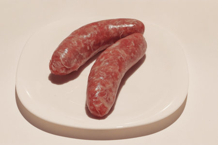Two fresh Italian sausages on a white plateの写真素材