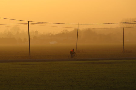 Cyclist along the road during winter sunset with hazeの写真素材