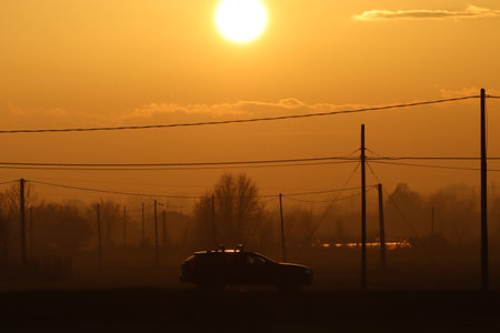 Family car on the road during winter sunset with hazeの写真素材