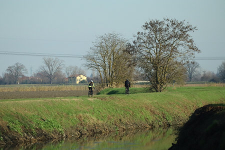 Couple in sports outfit cycling on a river embankment whit threesの写真素材