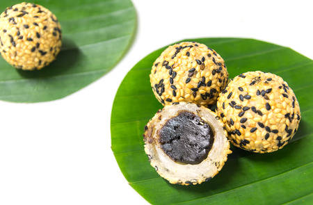 Deep fried sticky rice balls with black and white sesame, preserved jujube center filled on round shape banana leafの写真素材