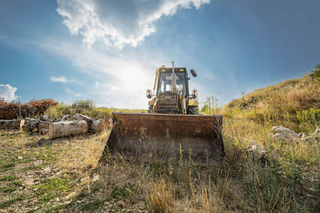 An old rusty shovel excavator in the backlight on a parking space
