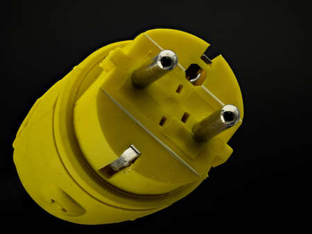 A yellow electrical plug with protective contacts