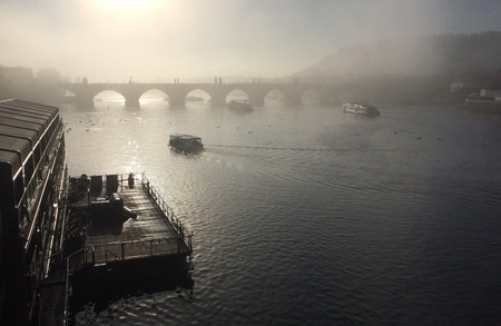 Charles Bridge shrouded in fog on the river with ships passing throughの写真素材