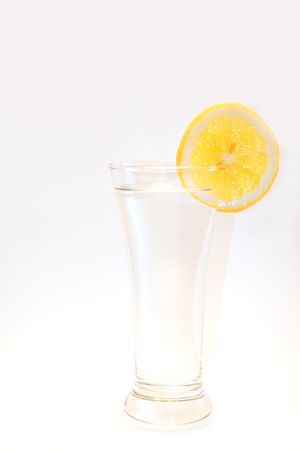 A clear glass of water with a slice of lemon on the rim on a white background.  Space for copy.の写真素材