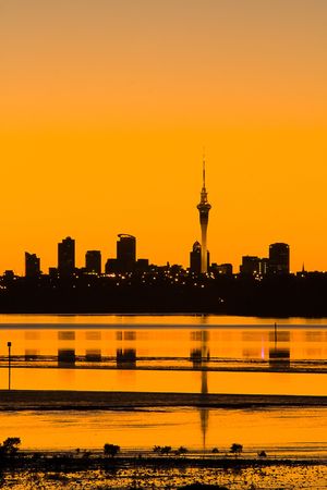 Auckland City in silhouette at sunrise viewed across the water, Auckland, New Zealandの写真素材