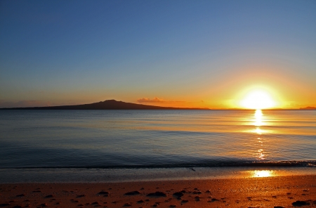 The dawn of a new day as the sun rises beside Rangitoto Island, Auckland, New Zealandの写真素材