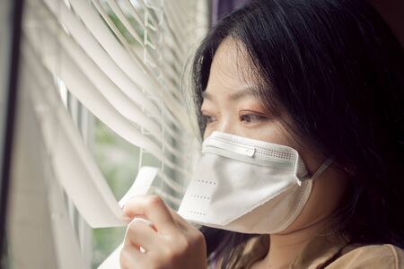 COVID-19 Pandemic Coronavirus Asian Woman Glancing Outside During Stay At Home Order.