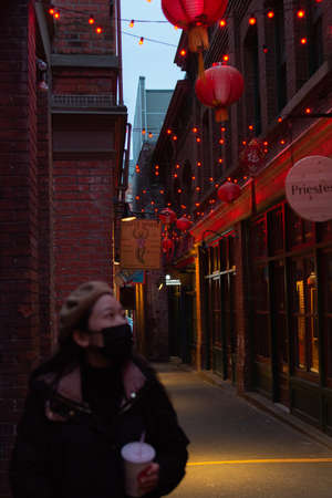 Woman in a medical mask walks down a narrow street in Boston.の写真素材