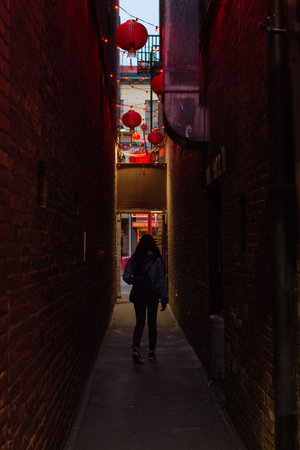 Woman walking in a narrow street at night.