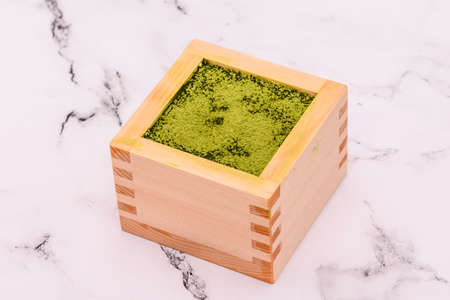 Japanese matcha green tea powder in wooden box on white marble background