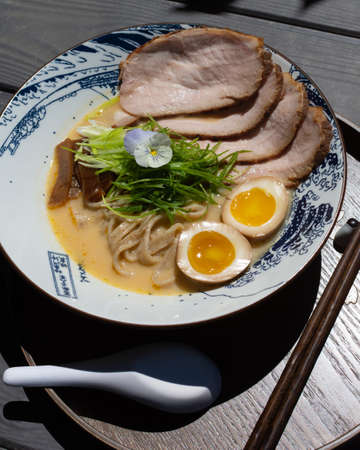 Japanese ramen with pork and egg in a bowl on a wooden table