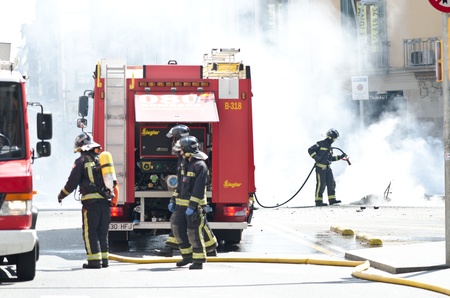 BARCELONA, SPAIN - MARCH 29: Fire workers slack one of the multiple fires caused by heavy riots during spanish general strike against labour reforms in the city center of Barcelona on March 29, 2912.のeditorial素材