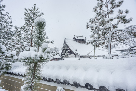 2017- Kenninji temple wood building behind a traditional Japanese wall on a snowy winter day with pine trees.のeditorial素材