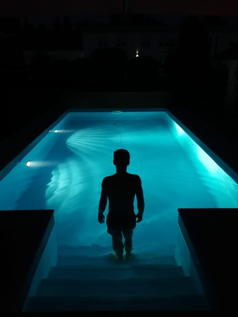 Silhoutte walking into the poolの写真素材